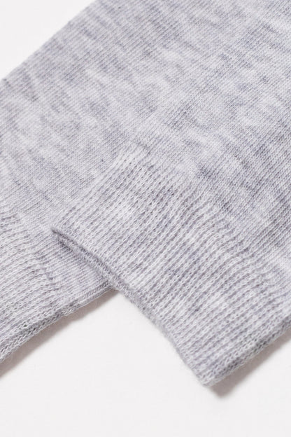 A close-up view of the ribbed cuff of a light grey heathered knit sock against a white background.