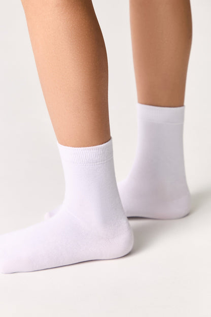 A pair of plain white ankle socks worn on feet against a clean, light-colored background.