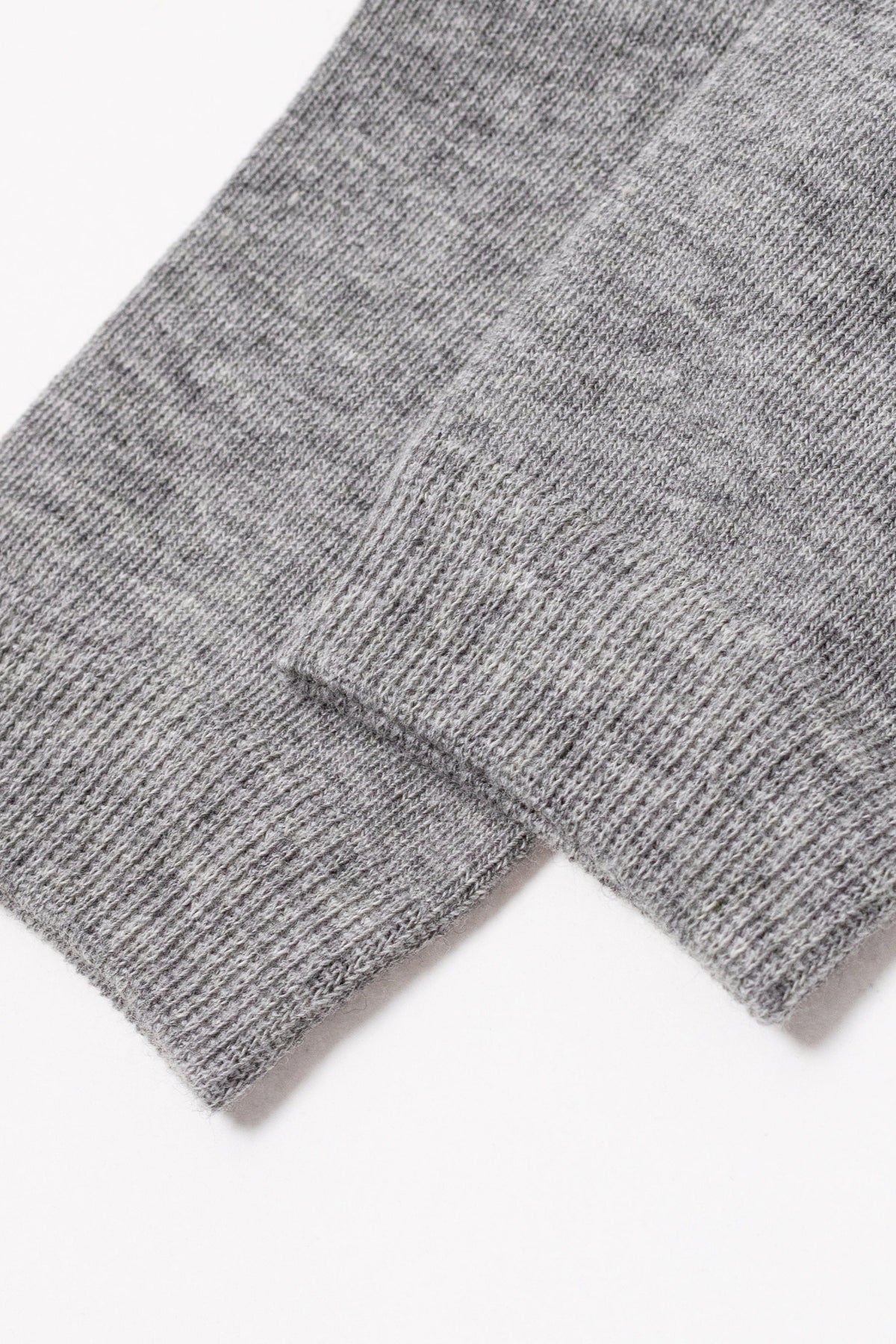 The sleeve cuffs of a grey knit sweater are displayed against a plain white background.