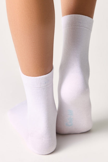 A pair of plain white ankle socks worn on the feet against a neutral background.