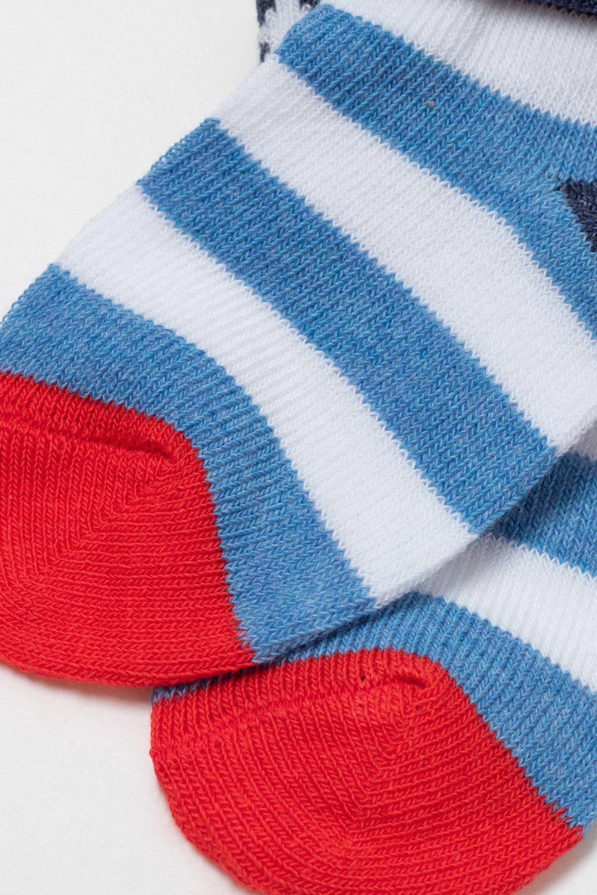A pair of folded socks featuring horizontal white and blue stripes with bright red toe sections against a plain white background.