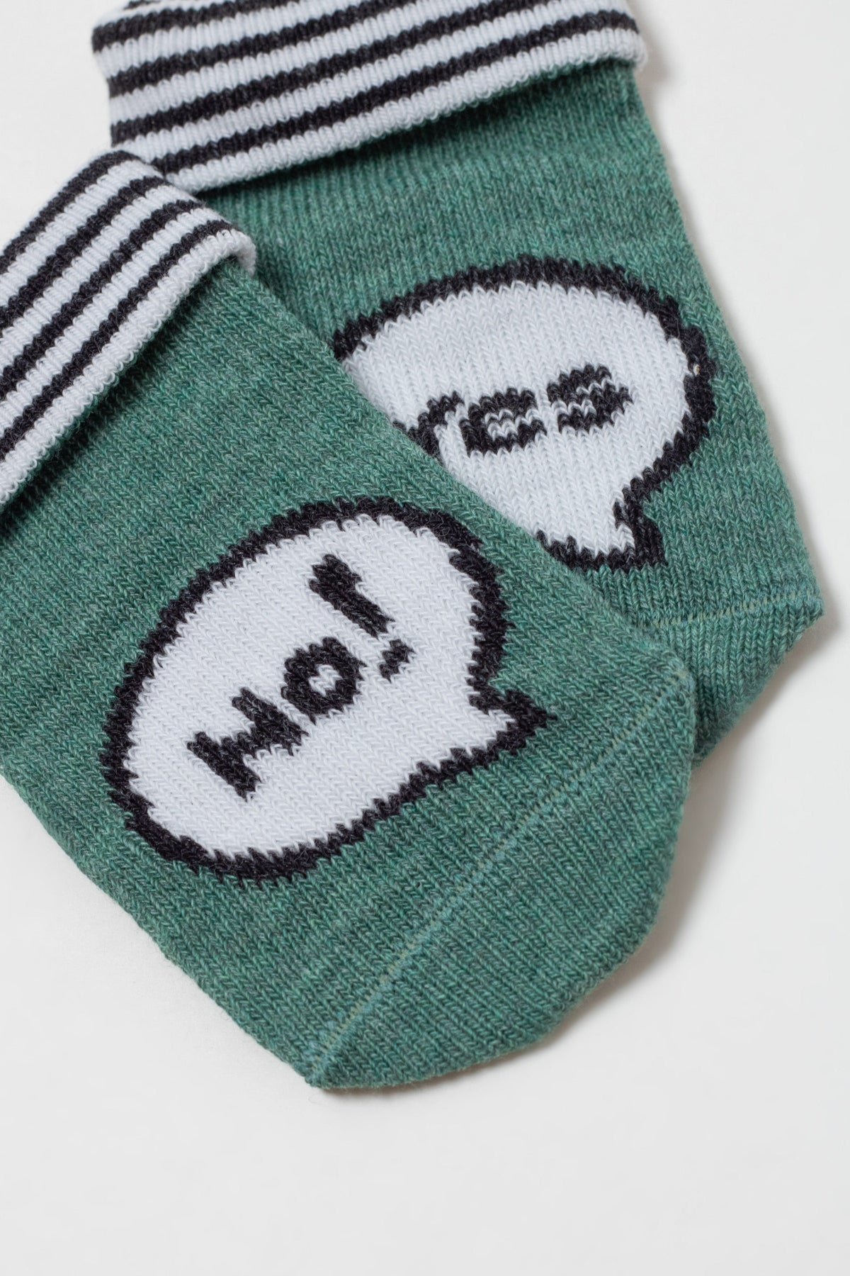A pair of folded green socks with black and white striped cuffs and white speech bubble graphics featuring the text Ho! and yes.
