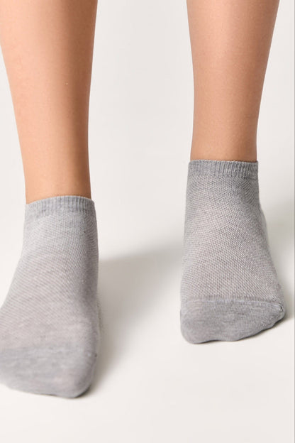 A pair of light grey ankle socks worn on feet against a plain white background.