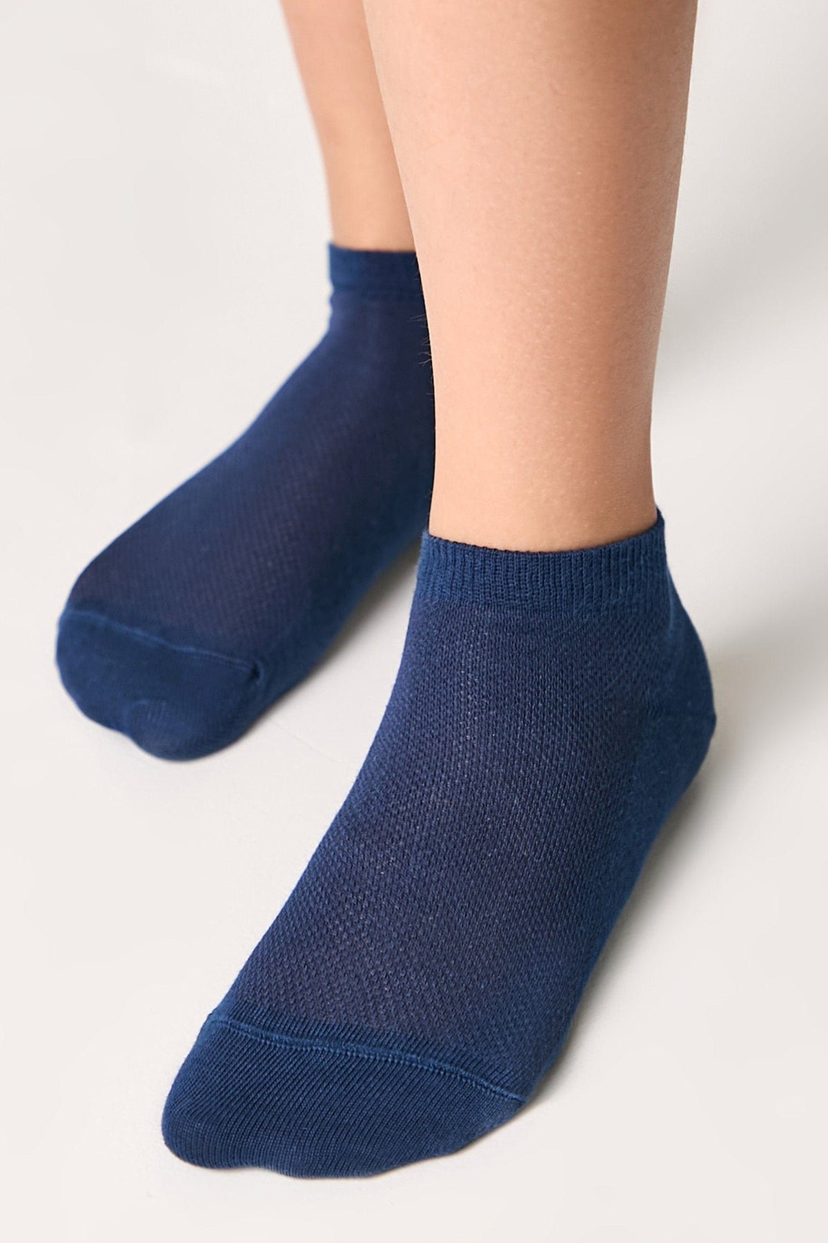A pair of ankle-length socks in a deep navy blue hue worn on a person's feet against a light background.