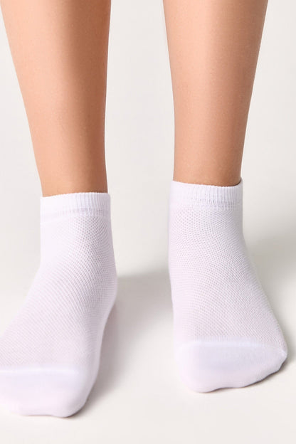 A pair of white ankle socks worn on feet against a plain background.