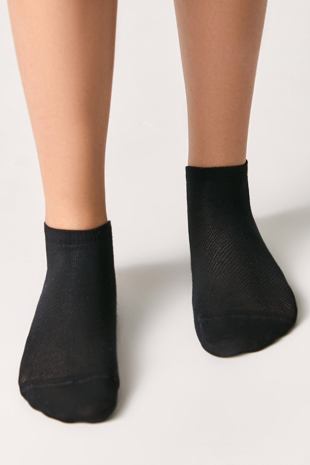 A pair of black ankle socks worn on feet against a plain white background.