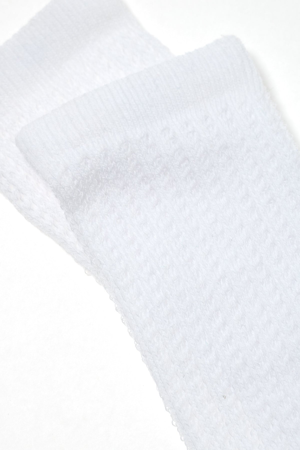 A pair of folded white athletic socks with a textured, ribbed fabric design shown against a plain white background.