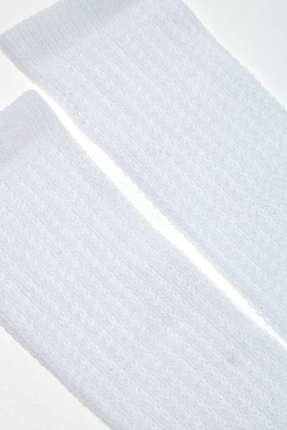 A pair of white textured mid-calf socks laid flat against a white background.
