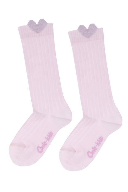 A pair of light pink knee-high socks featuring a ribbed texture and a sparkly lavender heart detail at the top edge, with the brand name printed in pink on the foot.