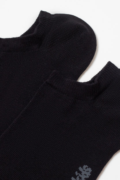 Two black low-cut ankle socks are folded and overlapping against a plain white background, showing their ribbed cuffs and a small gray detail near the edge of one sock.