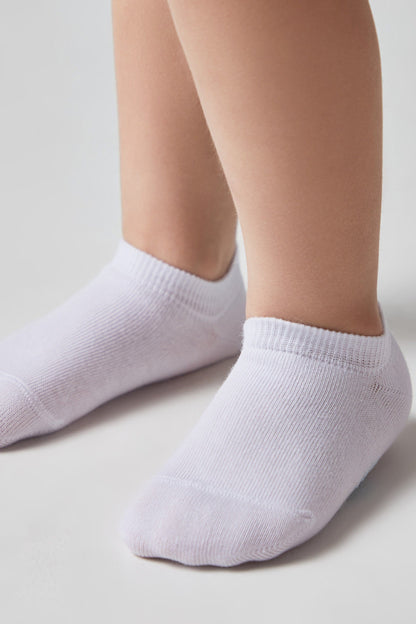 A pair of white low-cut ankle socks are worn on a person's feet against a plain light background.