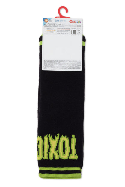 A pair of black children's socks featuring the word TOXIC in lime green lettering on the lower portion and lime green horizontal stripes at the toe and cuff, presented on a cardboard hang tag.