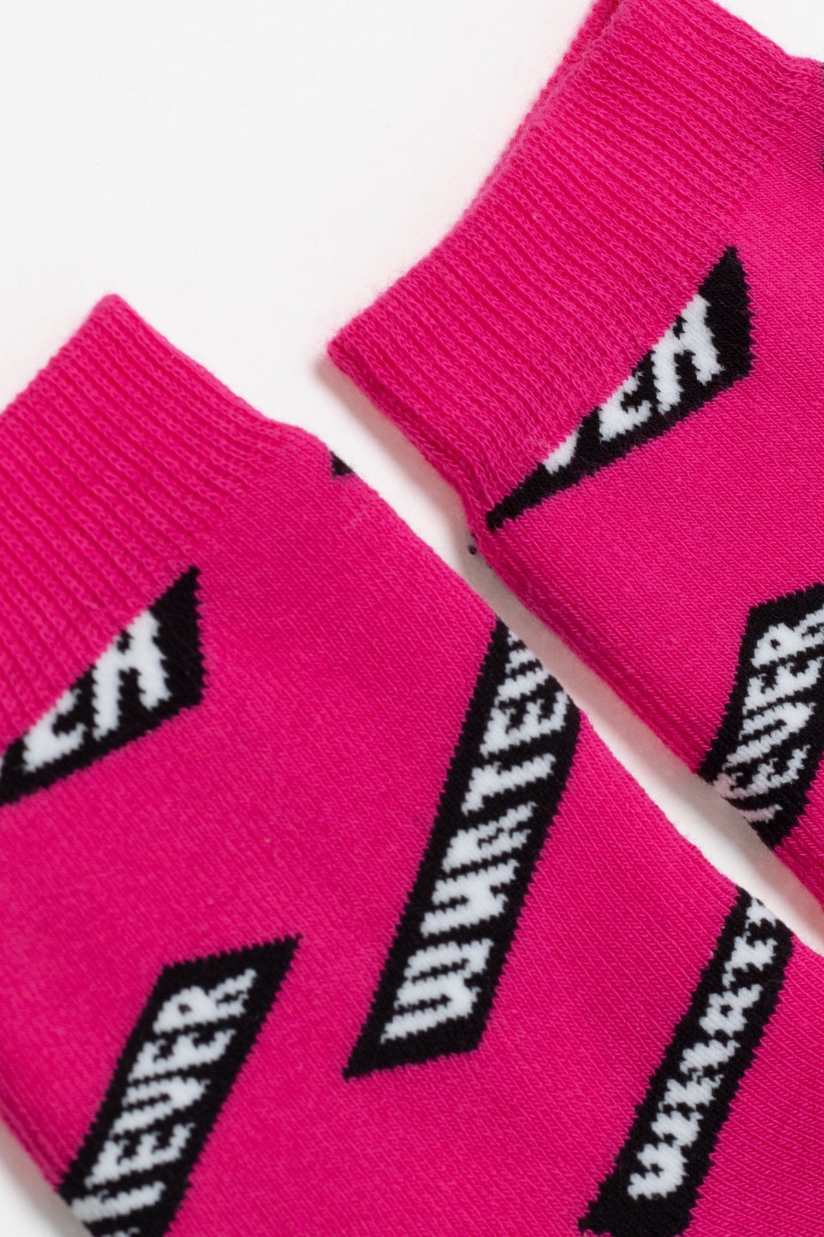 A close-up view of bright pink socks featuring a repeating black and white pattern of the word whatever inside a slanted rectangular block.