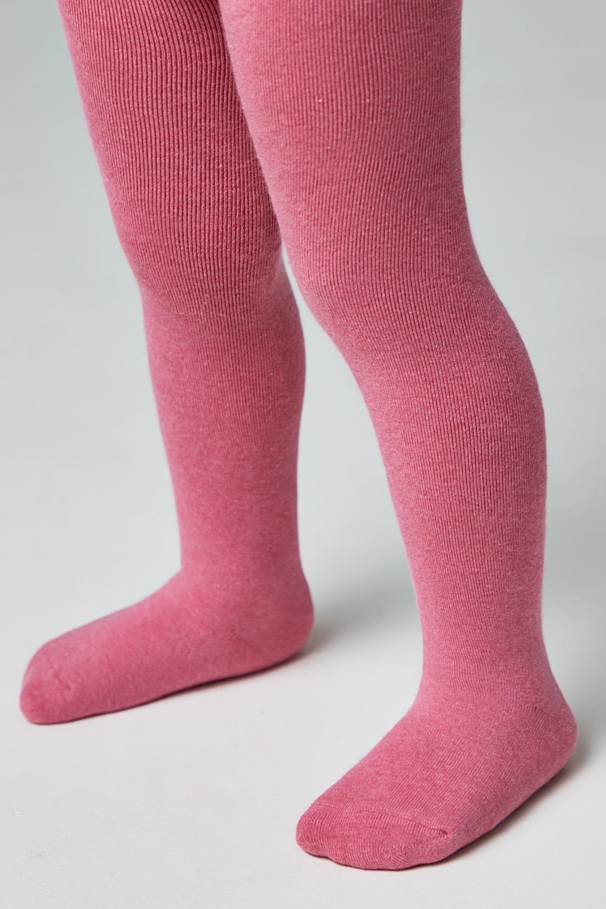 A pair of textured, vibrant pink tights worn on a child's legs against a plain white background.
