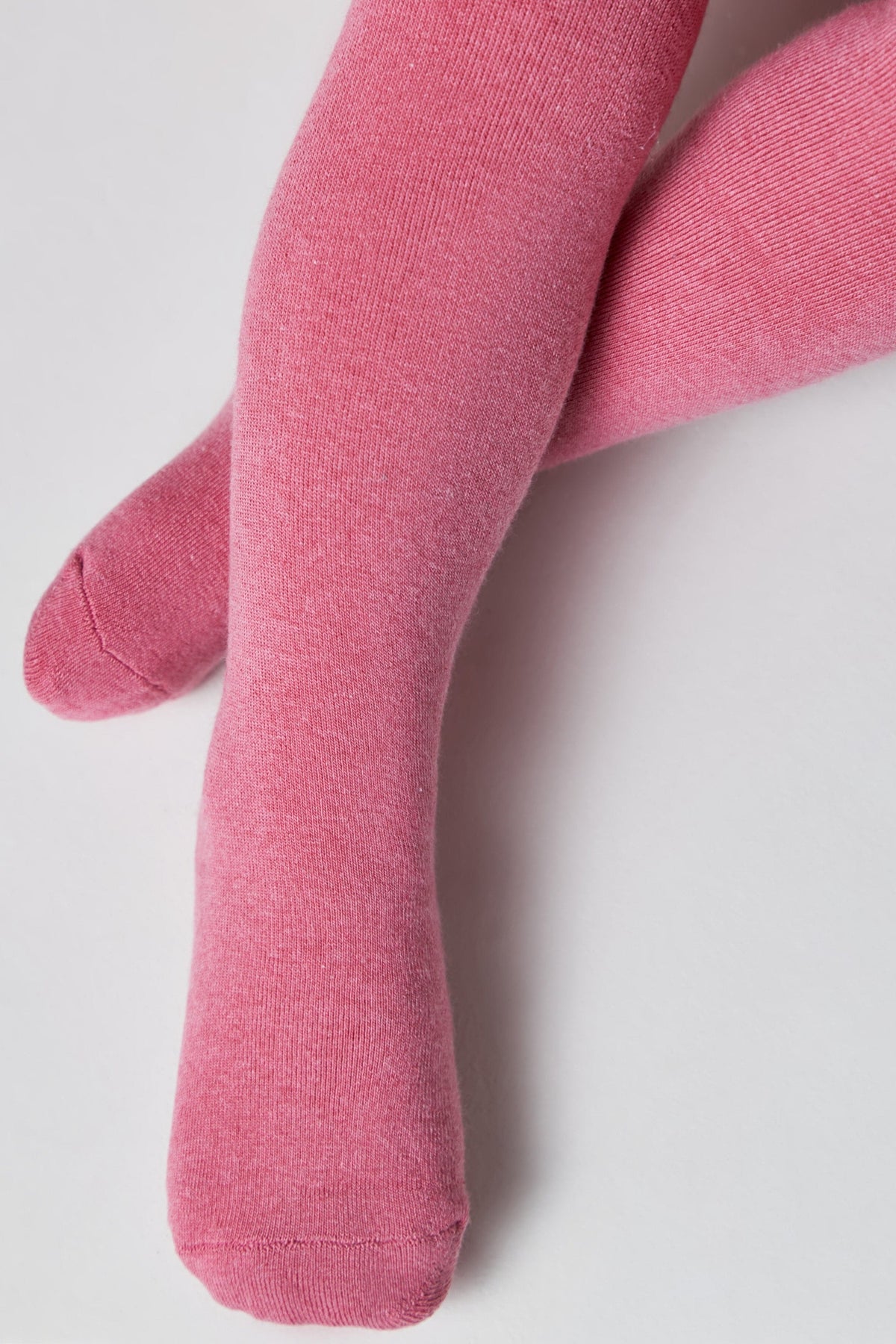A pair of children's tights in a solid, heathered pink color, displayed with legs crossed against a plain white background.