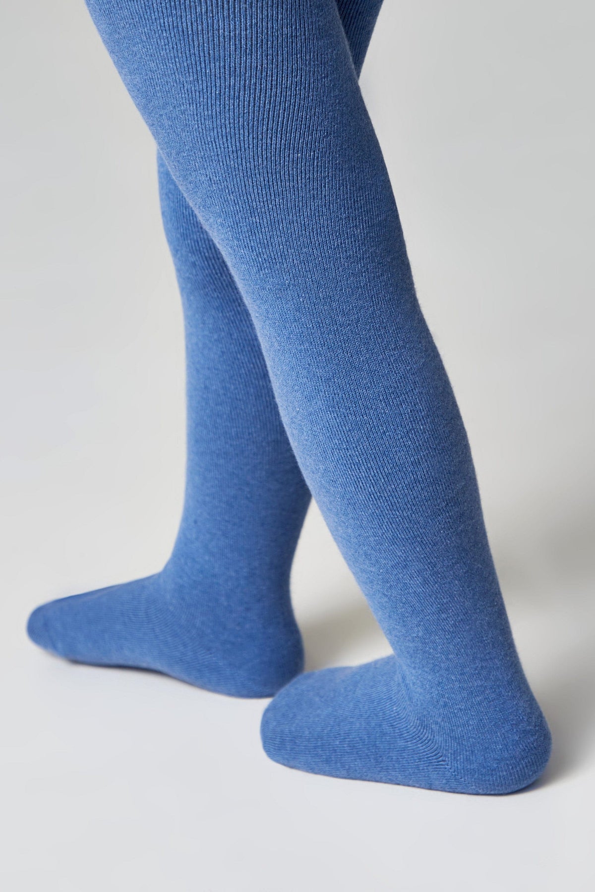 A pair of ribbed tights in a vibrant blue color, shown on a person's legs against a plain light gray background.