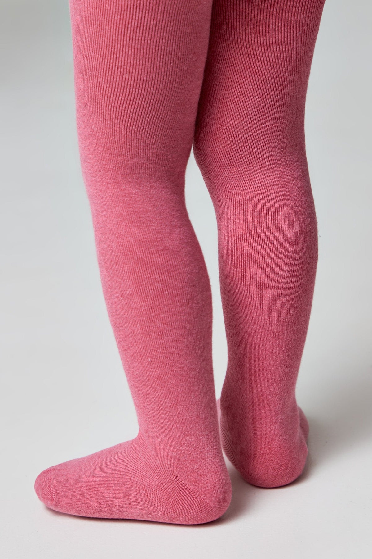 A pair of children's ribbed tights in a solid pink colour shown from the back against a plain white background.