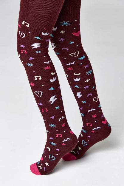 A pair of dark maroon tights patterned with small, colorful icons including musical notes, hearts, lightning bolts, stars, and abstract shapes, shown on legs against a plain white background.