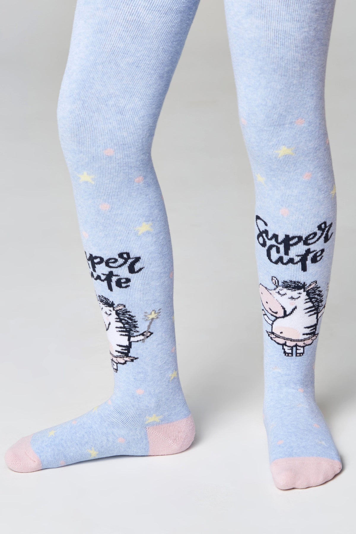 Light blue children's tights featuring a repeating pattern of small stars and a graphic of a zebra with a tutu and wand accompanied by the text 'Super Cute' on each leg, finished with solid pink toe and heel sections.