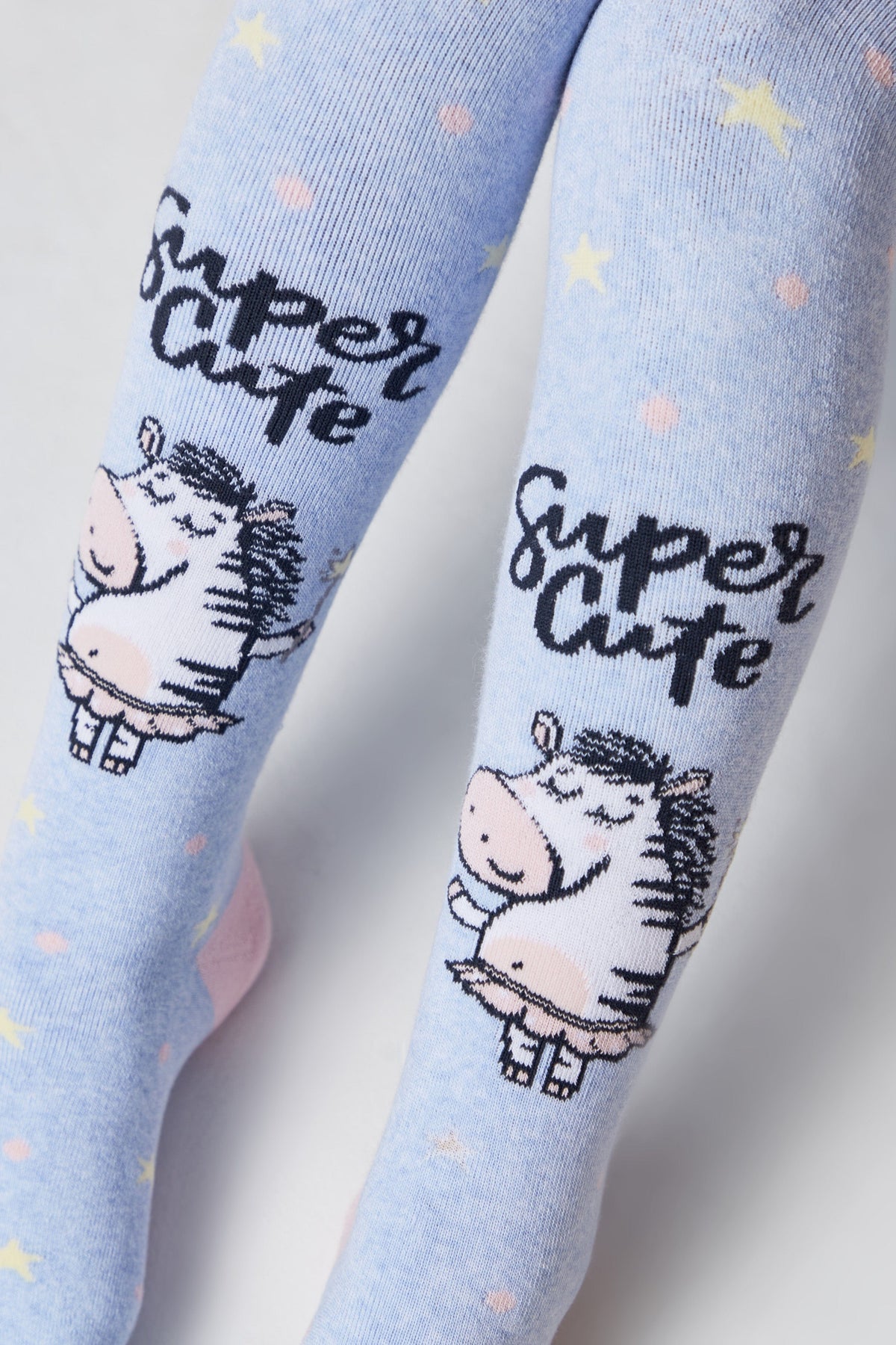 Light blue tights patterned with yellow stars, pink dots, and cartoon zebras wearing tutus, featuring the text Super Cute printed in black script.