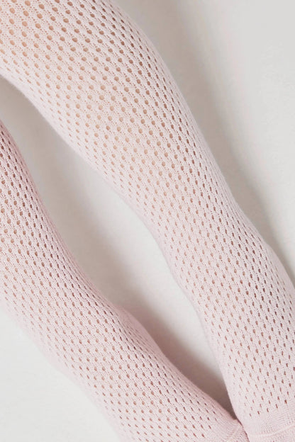 A close-up view of two legs wearing pale pink, fine-knit, open-weave tights against a plain white background.