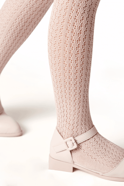 A pair of pale pink textured knit tights paired with matching buckled Mary Jane shoes on a white background.