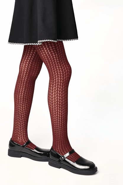 Burgundy knit tights with a vertical textured pattern worn with a black skirt and glossy black Mary Jane shoes.