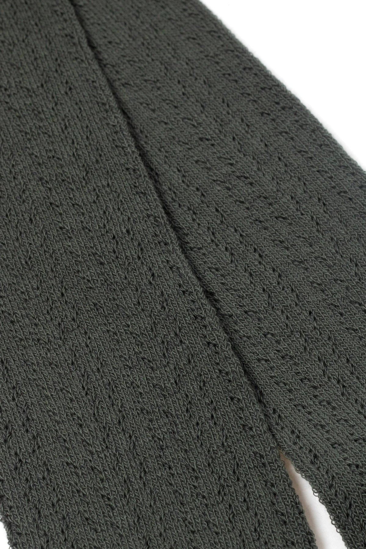 A close-up of dark grey, textured knit fabric with a visible seam running vertically down the center.