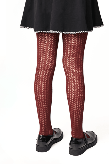 A pair of maroon cable knit patterned tights paired with a black skirt and black buckled loafers.