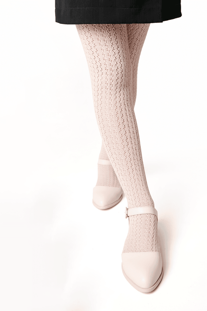 Light pink knit tights with a decorative textured pattern worn with light pink buckled Mary Jane shoes.