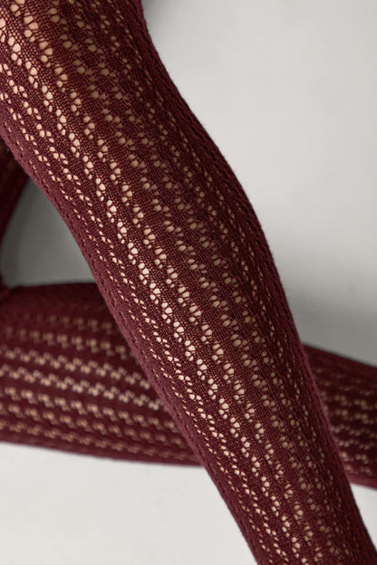 A pair of deep burgundy tights with a vertical openwork pointelle knit pattern covering the fabric.