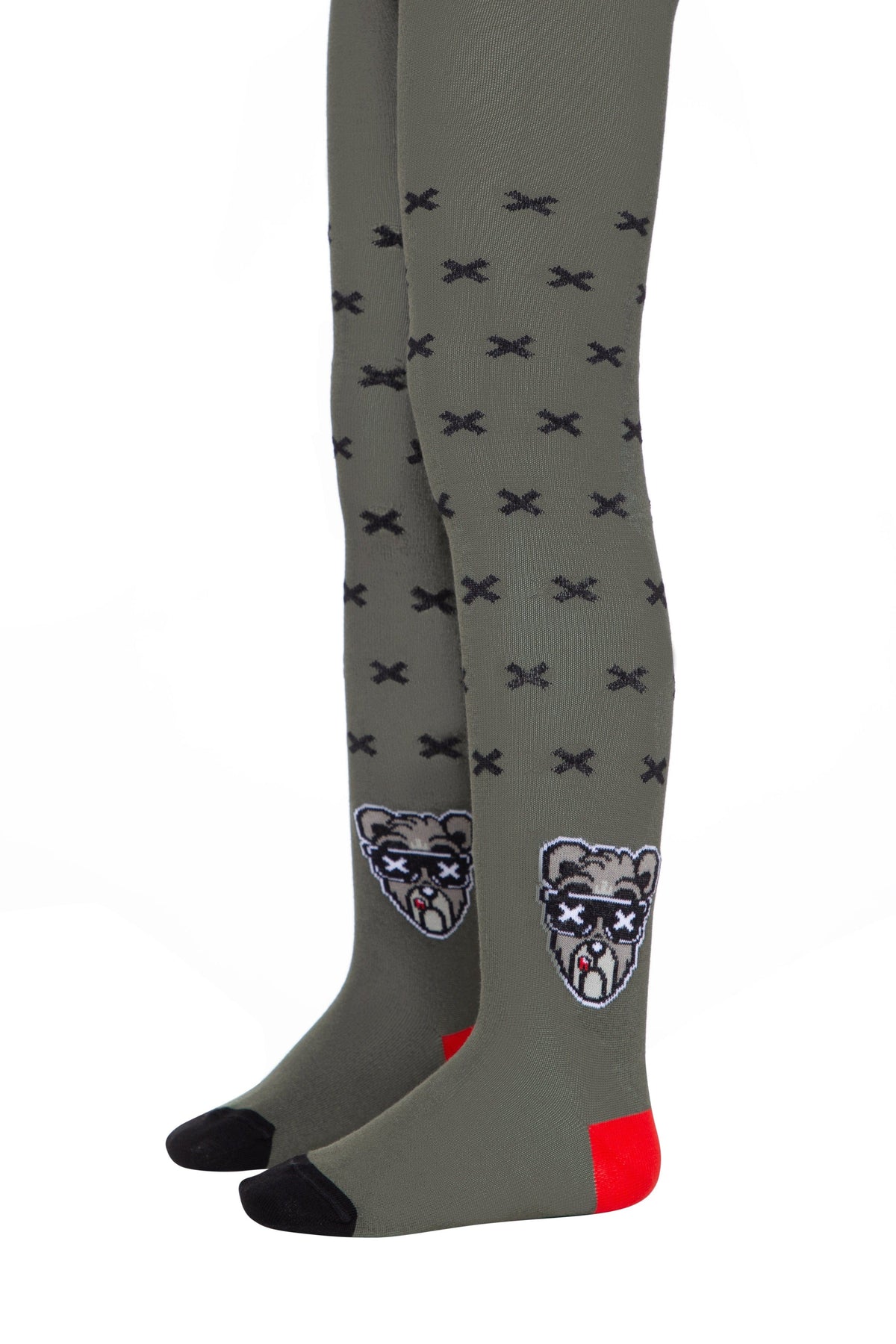A pair of olive green tights features a repeating pattern of small black crosses and a cartoon bear face wearing sunglasses on each ankle, accented with black toe caps and bright red heel patches.