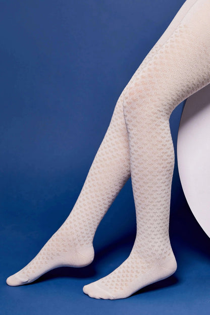 Patterned cream-colored tights worn on a model's legs against a solid blue background.