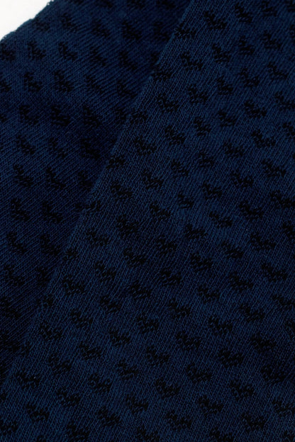 A close-up of dark navy blue fabric featuring a textured geometric pattern of small, repeating shapes.
