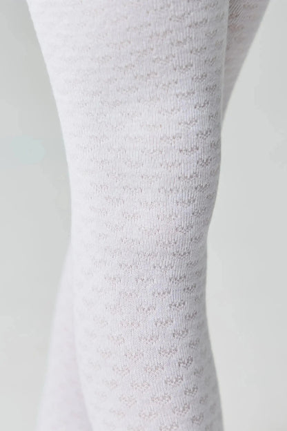 Close-up view of white opaque tights featuring a subtle, repeating heart pattern texture against a plain light gray background.