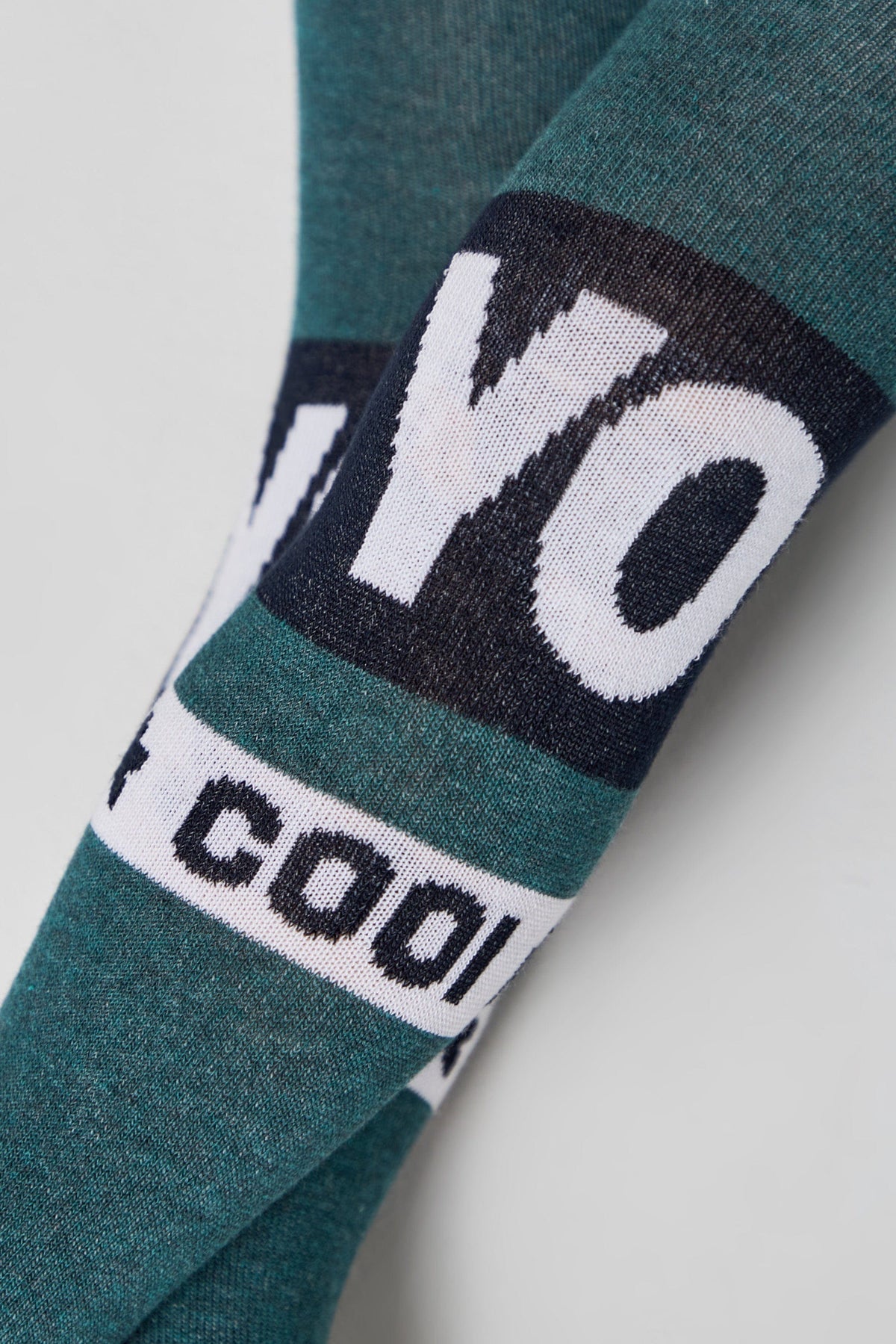 Close-up of teal fabric featuring horizontal bands of white text that reads YO and COOL against a dark blue background.