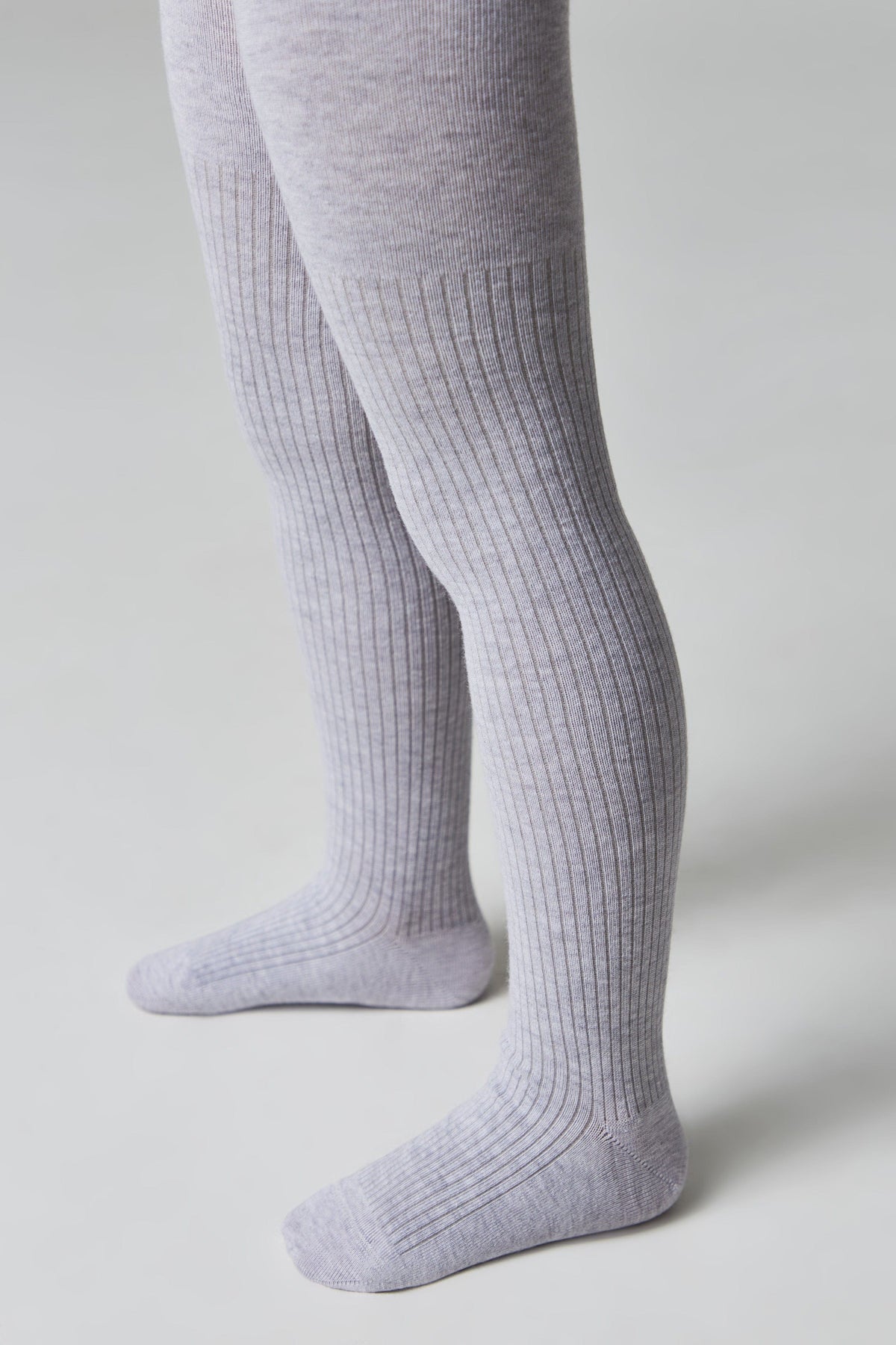 Light grey ribbed tights worn on a person's legs against a plain white background.