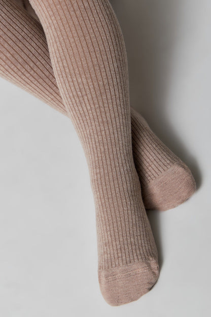 A pair of light tan ribbed knit tights worn on legs, angled against a plain white background.