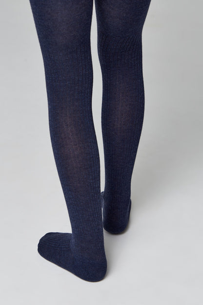 A pair of ribbed, dark navy blue footed tights worn on a person's legs against a plain light grey background.