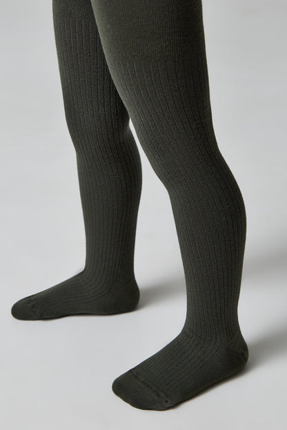 A pair of dark olive green ribbed tights worn on a child's legs against a plain light gray background.