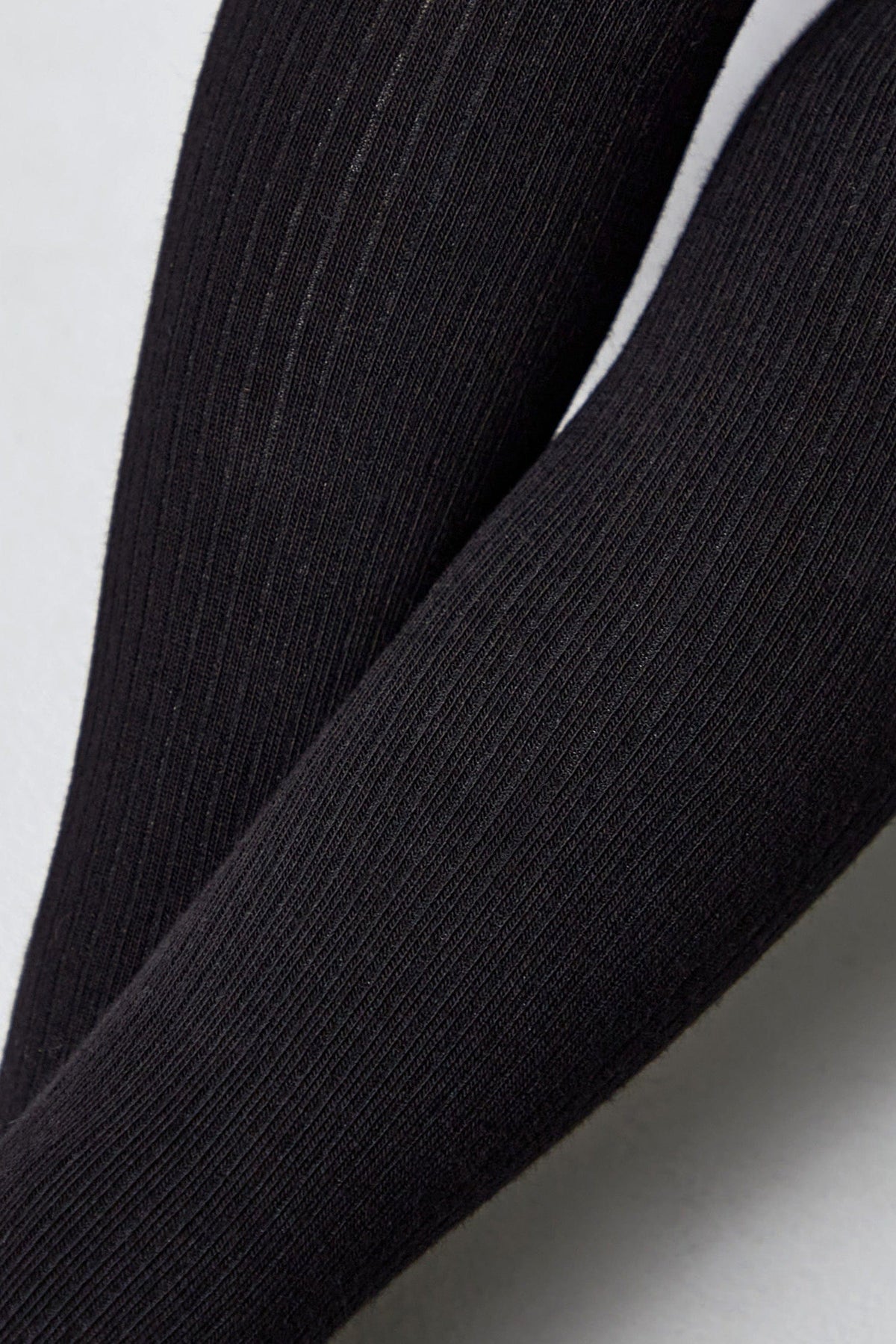 A close-up view of black ribbed tights showing the detailed vertical texture of the fabric.