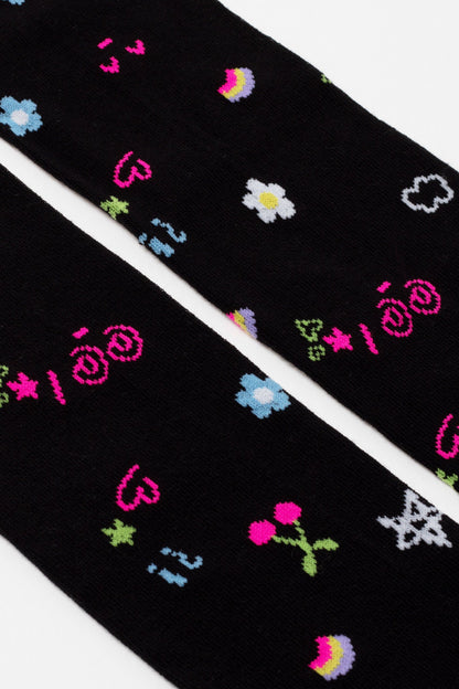 A pair of black socks featuring a colorful all-over print of small icons including flowers, hearts, cherries, rainbows, clouds, and stars.