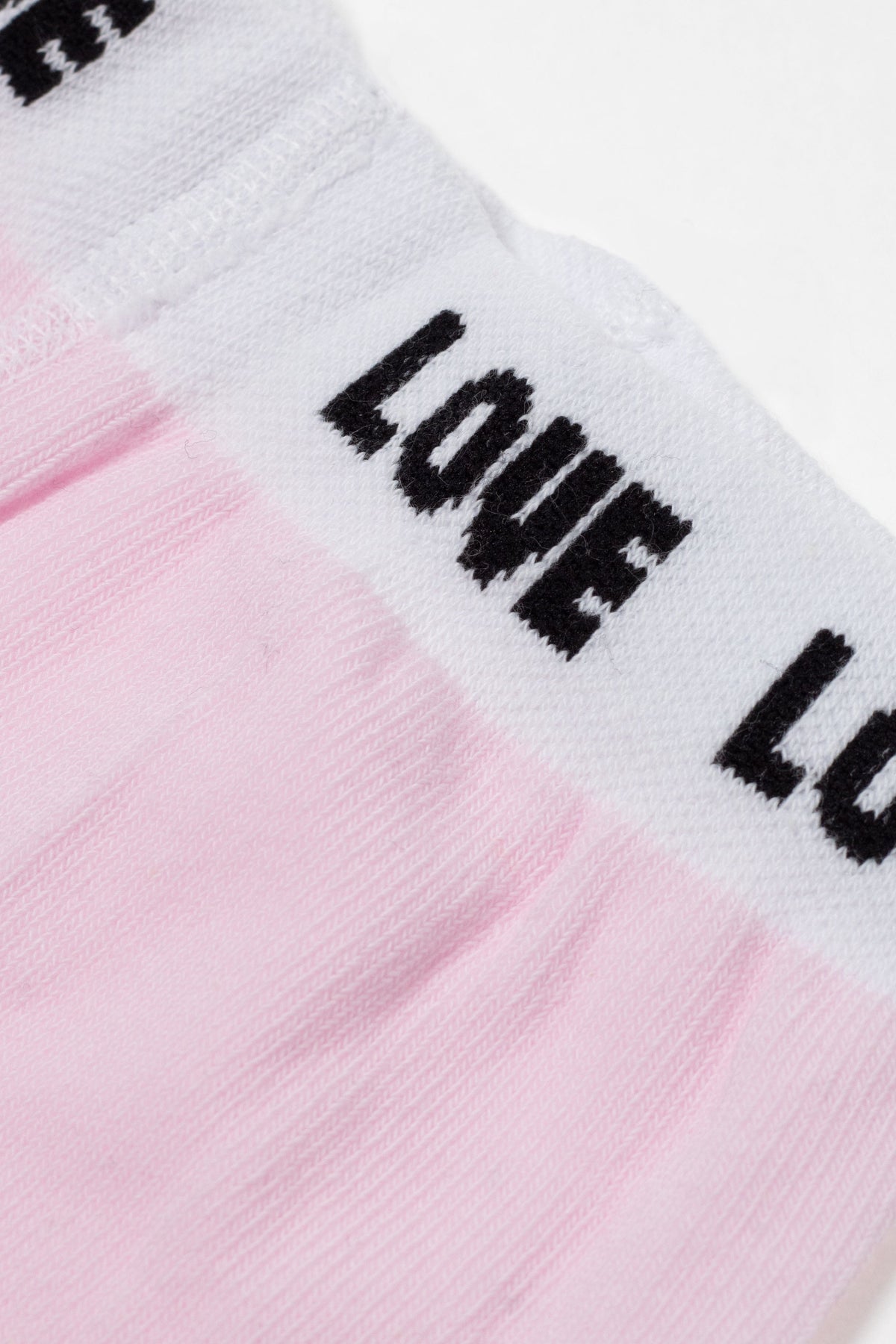 A close-up of a light pink garment featuring a white elastic waistband with the word LOVE printed in repeating black block letters.