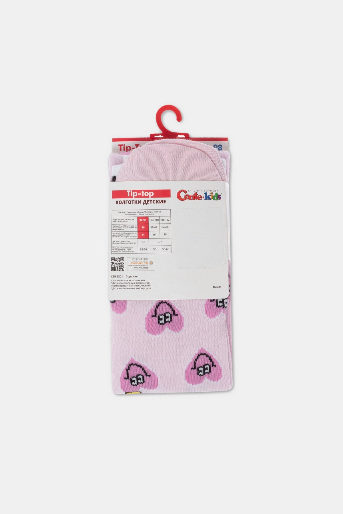 Pink children's tights featuring a repeating pattern of white hearts with black outlines and pink centers, displayed on a cardboard hanger with a size chart.