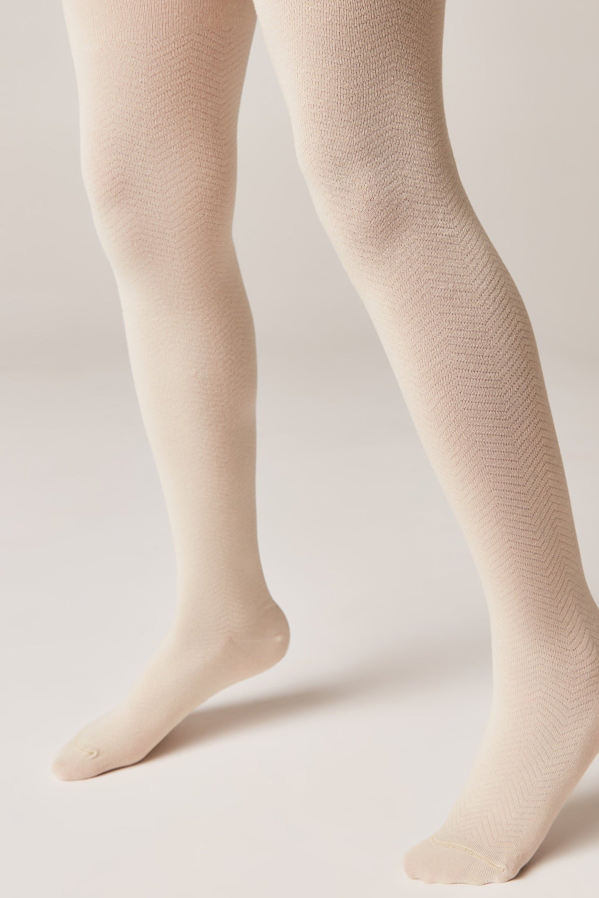 Beige textured tights worn on a pair of legs against a plain light-colored background.