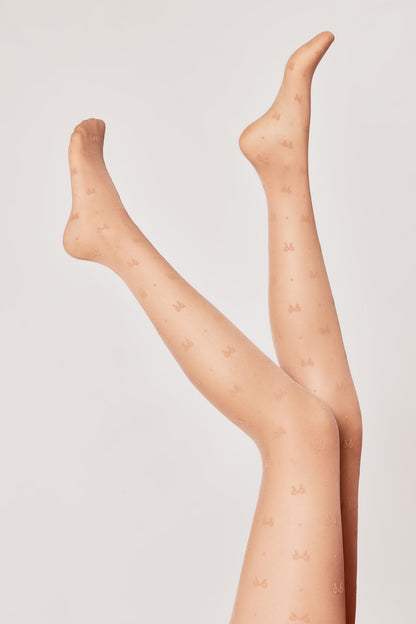 Sheer nude-toned tights with a repeating pattern of small bows are modeled on a pair of raised legs against a plain light gray background.