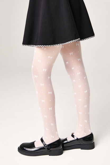 Sheer white tights decorated with a repeating pattern of small bows are worn with a black skirt and black mary jane shoes.