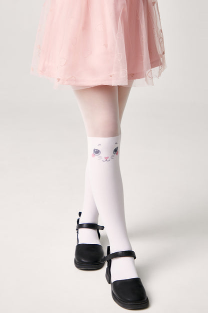 A pair of white tights featuring a cute cat face illustration on the knee, worn with a pink skirt and black buckled flat shoes.