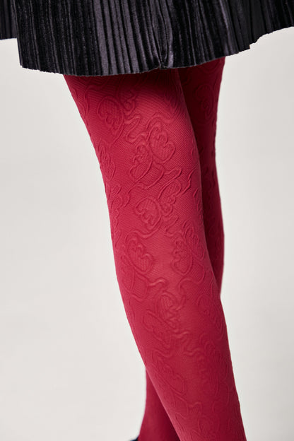 Bright red patterned tights worn with a dark pleated skirt.