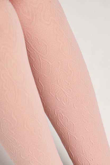 A close-up of light pink tights featuring a subtle, raised floral damask pattern woven into the fabric.